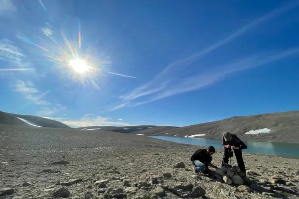 Photograph of people standing by arctic lake.