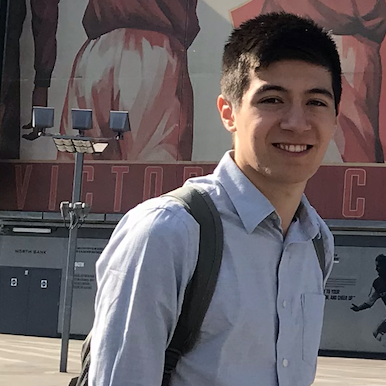 Benjamin standing and smiling in front of some buildings. 