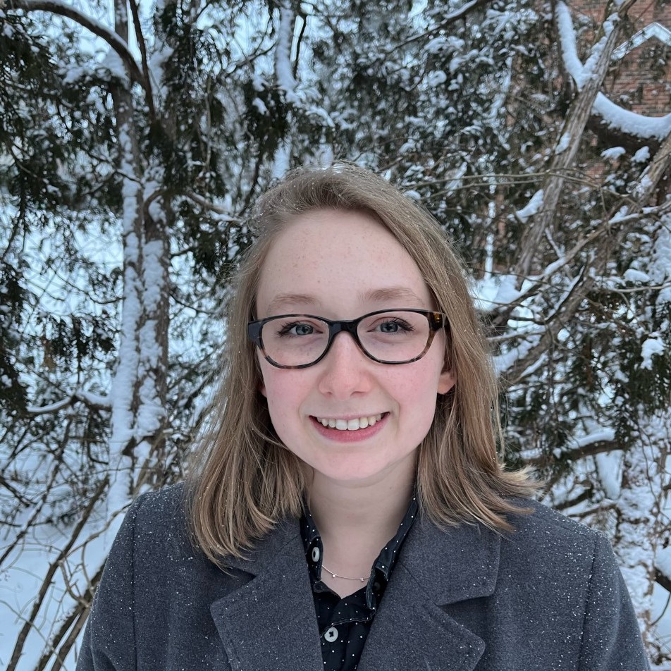 Hannah smiling in front of snowy trees. 