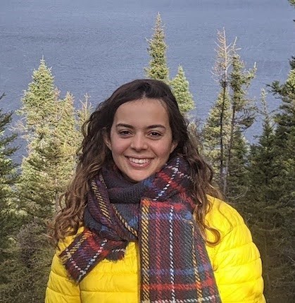 Hannah smiling in front of trees and a lake. 