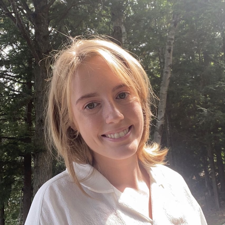 Sophia smiling in front of trees.