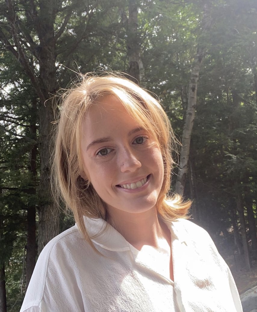 Sophia smiling in front of trees.