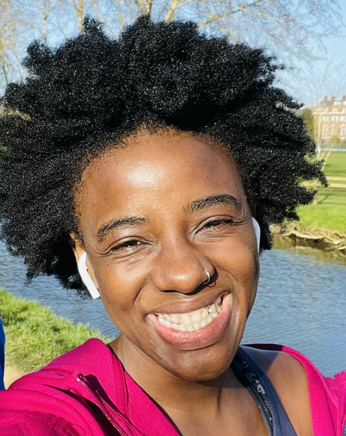Nokuzola smiling with a grassy riverbank in the background.