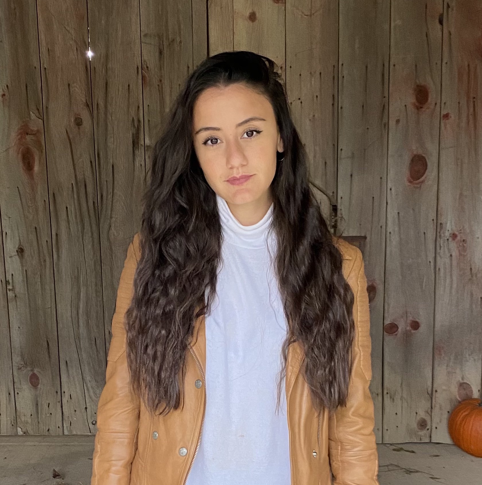 Melissa smiling in front of a wooden wall. 