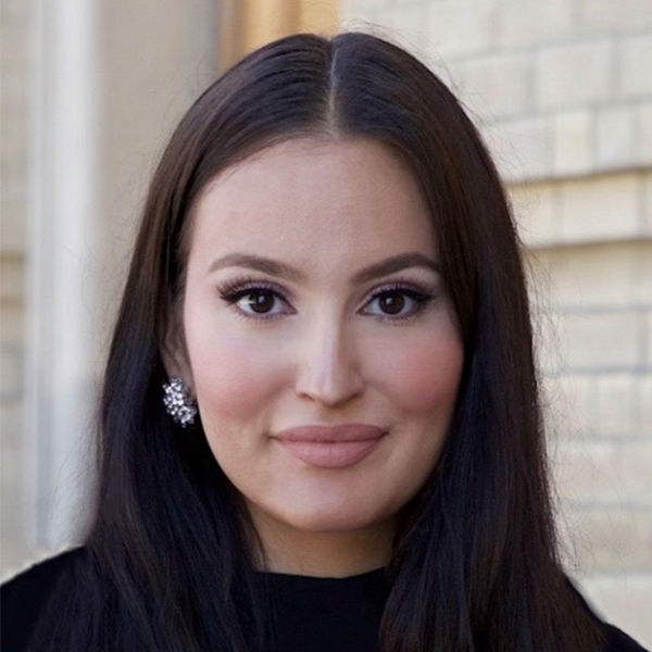 Jasmine smiling, with a blurred stone building in the background.