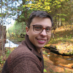 Jeff sitting and smiling in front of a stream. 