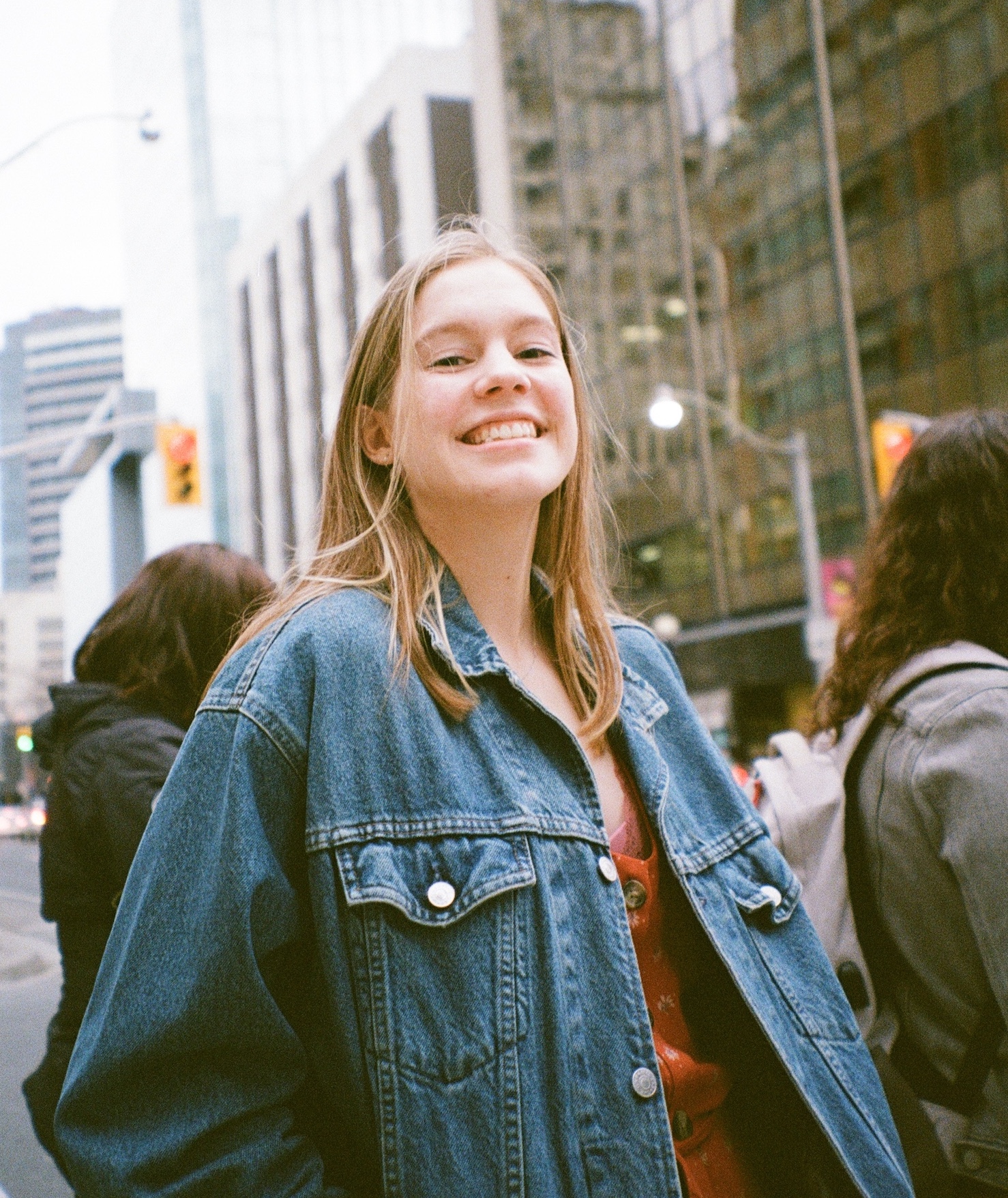 Kate smiling in the sun in front of some buildings. 