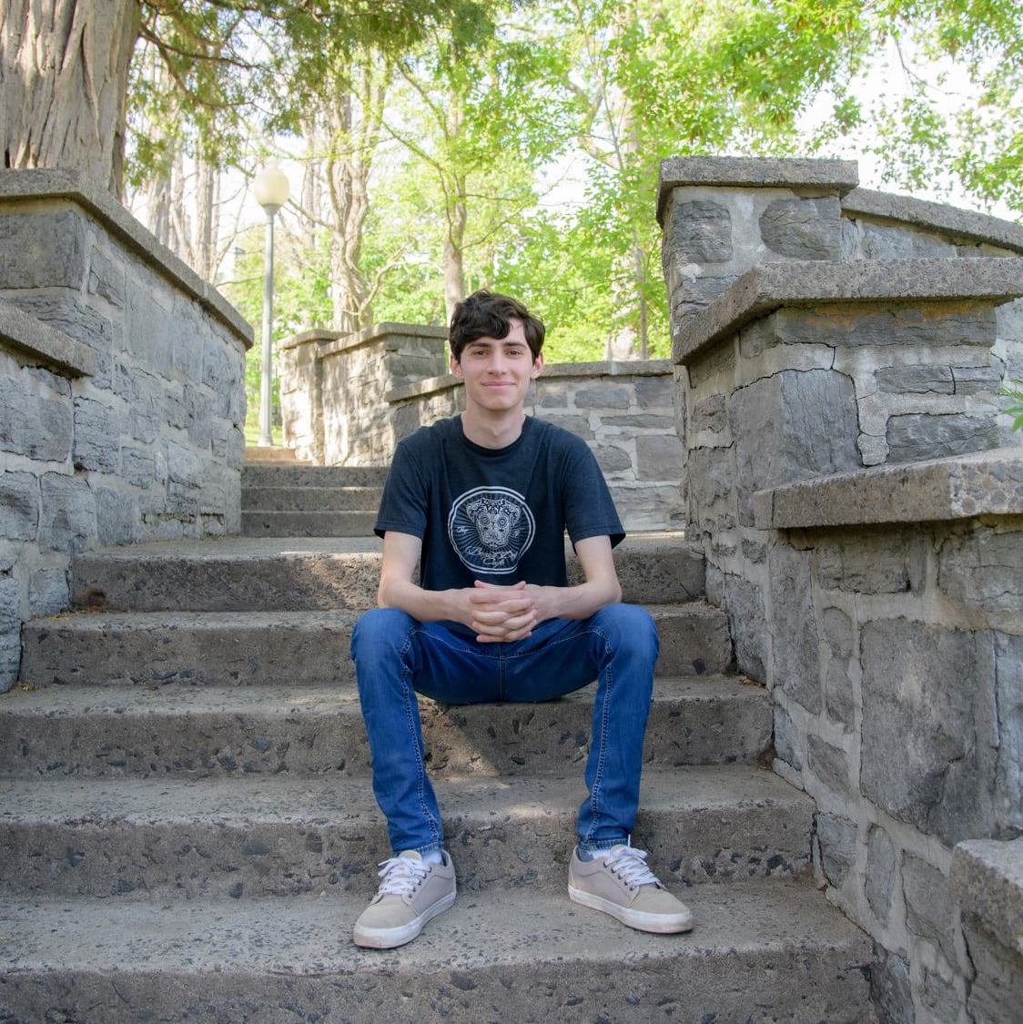 Oliver sitting and smiling on stone steps. 