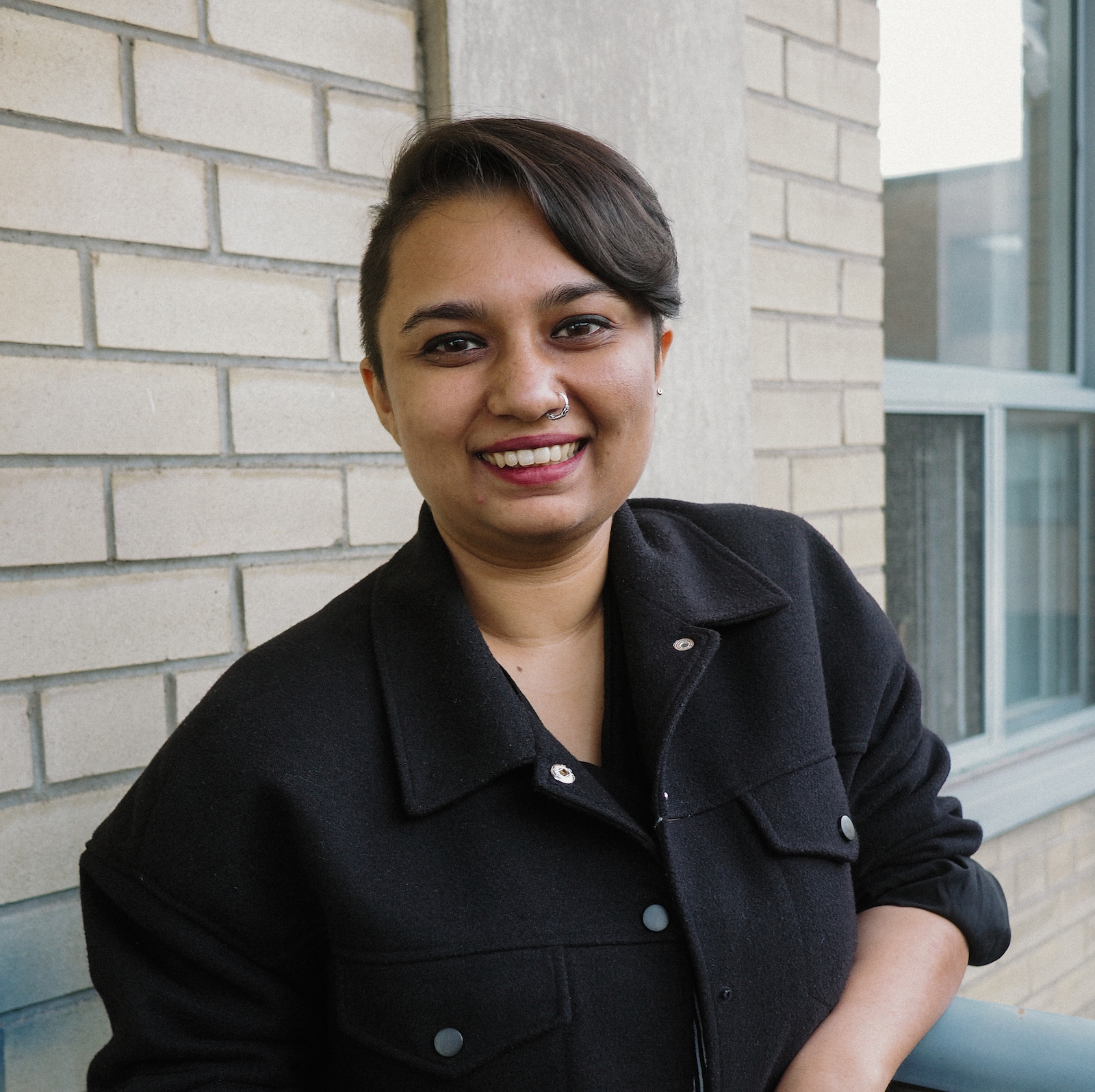 Pragya smiling in front of a wall. 