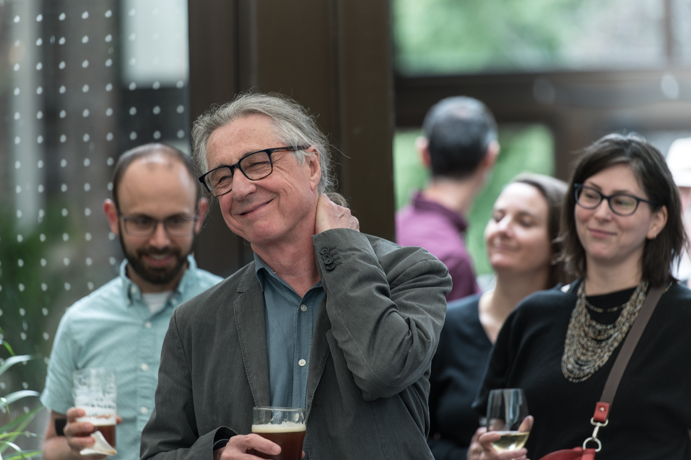 Robert holds a beer and smiles among a crowd of people