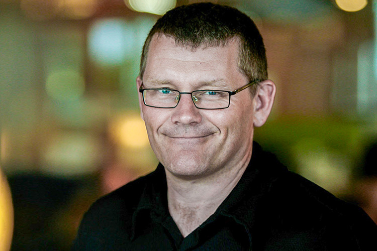 Portrait of Scott Prudham smiling, background blurred