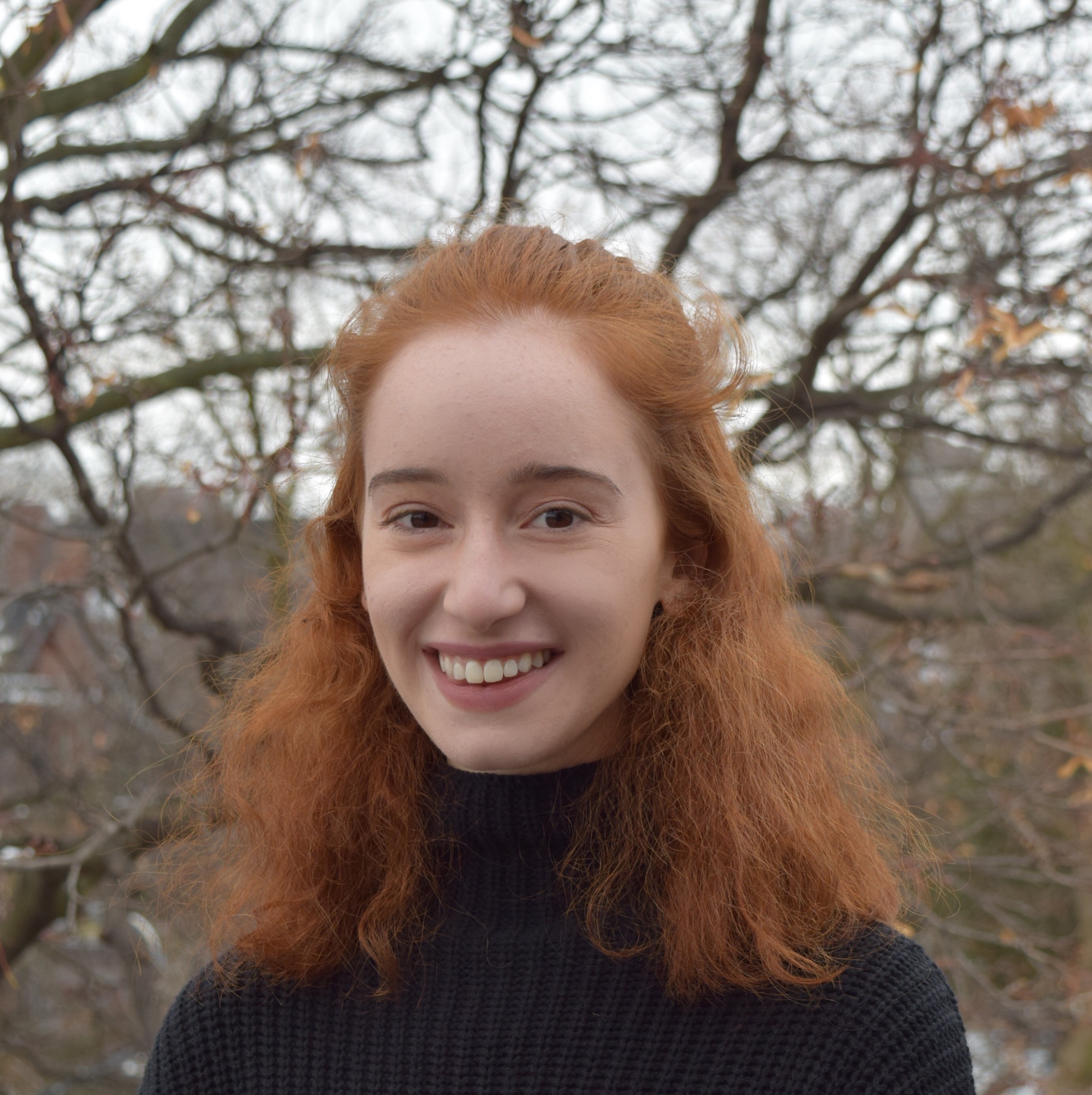 Shulie smiling in front of trees. 