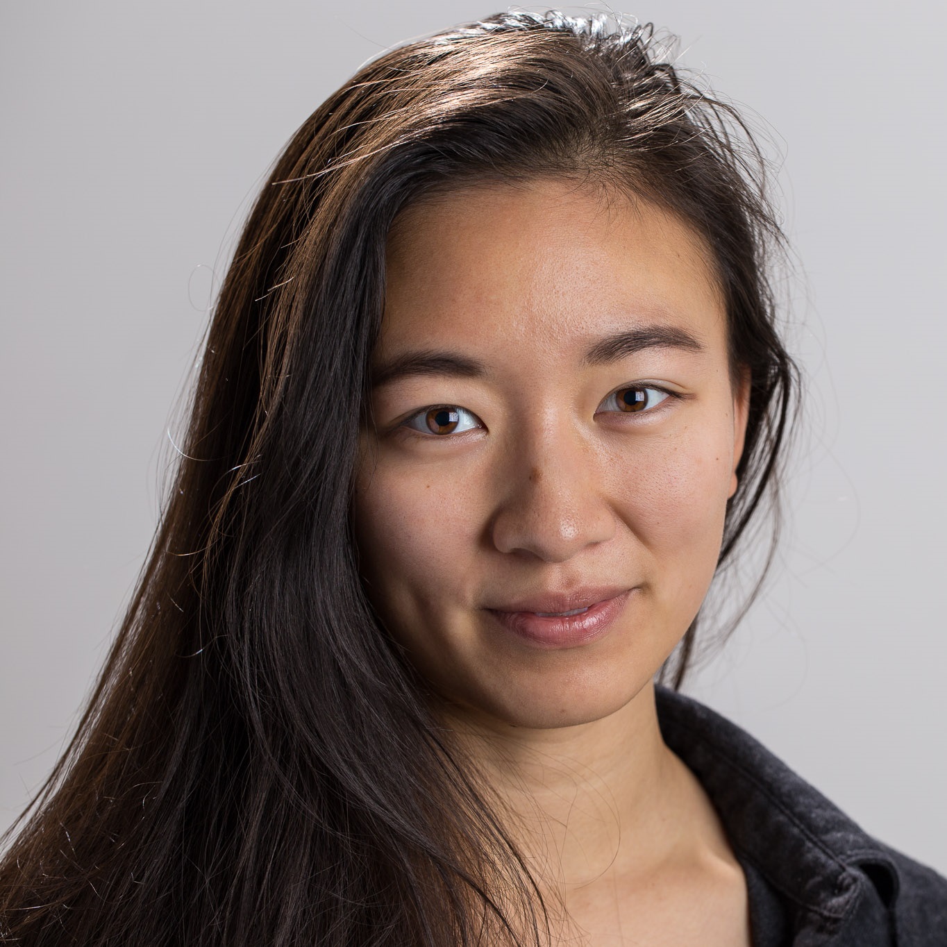 Chiyi smiling in a black shirt in front of a grey background.