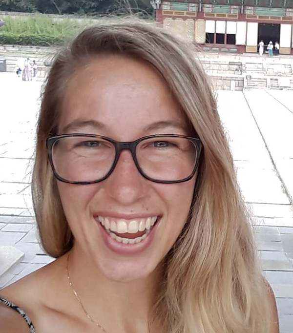 Victoria smiling and standing in a courtyard. 