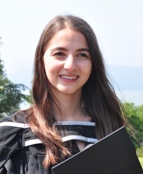 Ecce smiling holding a graduation cap. 