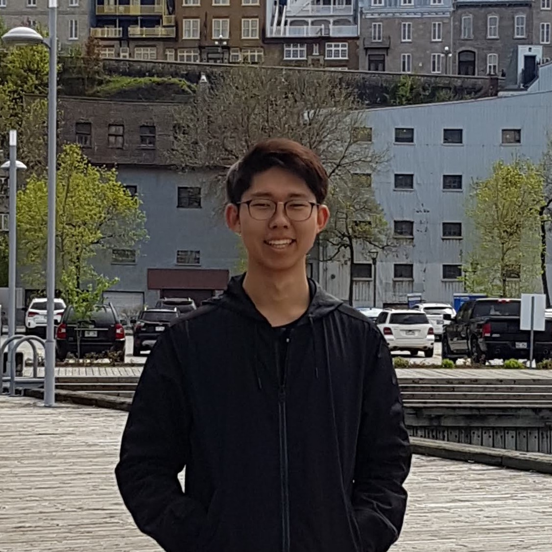 Ian smiling on a pier in front of some buildings.