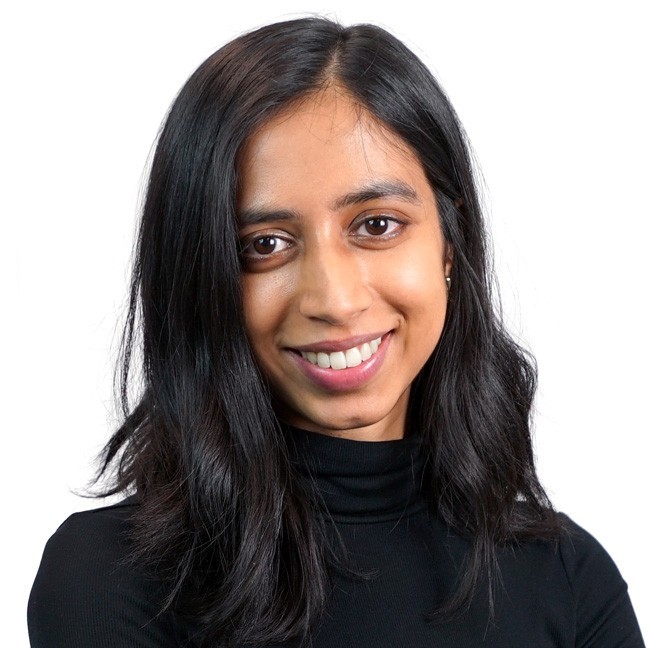 Priya smiling in front of a white background.