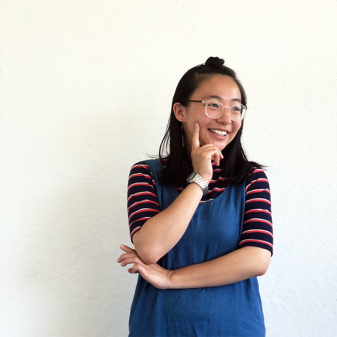 Christa smiling in front of a white wall.