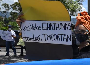 A member of the Garifuna ethnic group holds a sign reading &amp;quot;Garifuna Lives Also Matter&amp;quot;