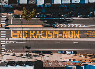 Aerial photograph of a city street. Graffiti on the street reads &amp;#039;End Racism Now&amp;#039;