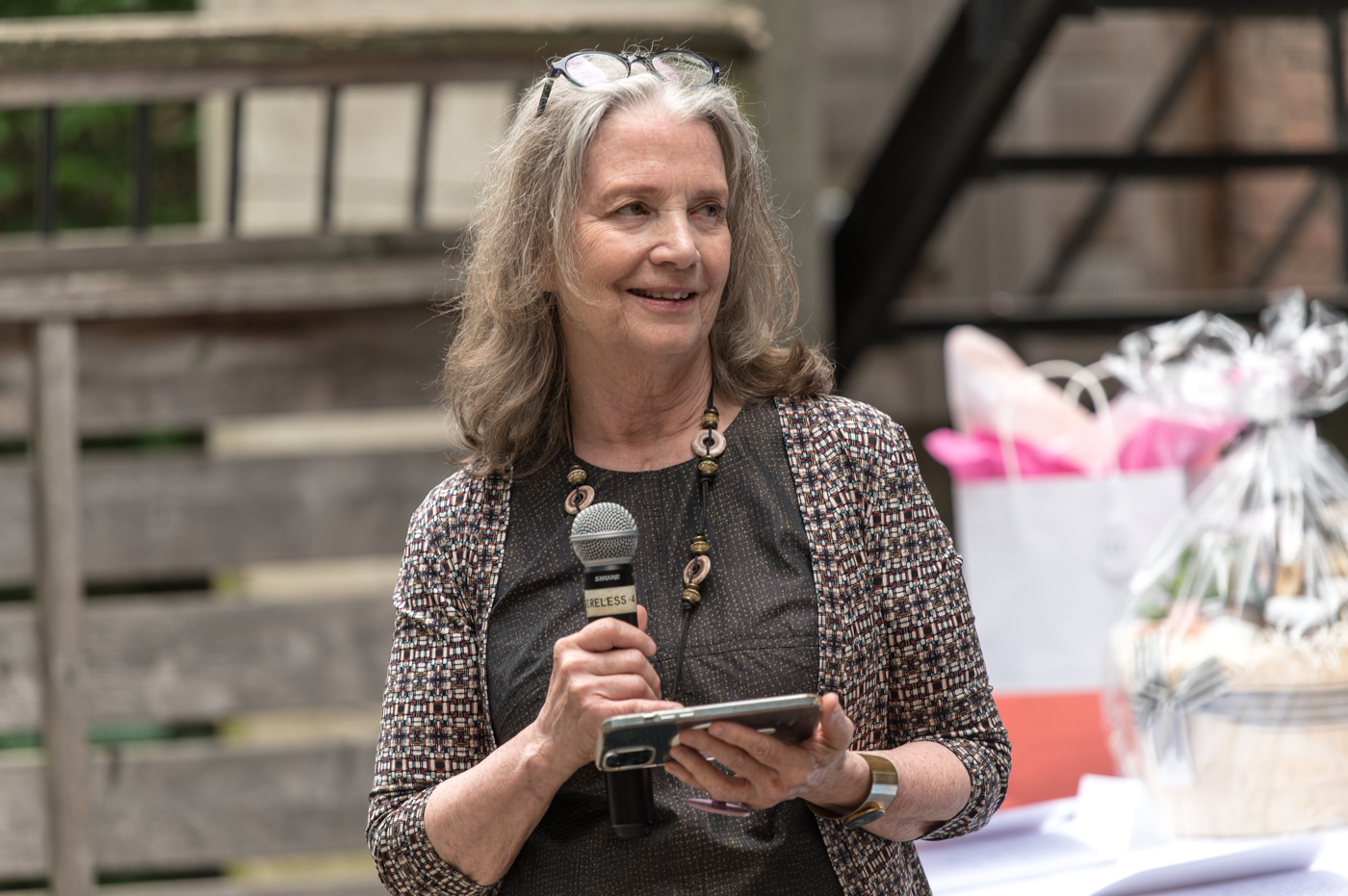 Sue holds a microphone at outdoor event
