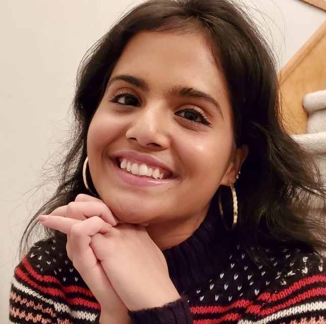 Grihalakshmi smiling and sitting on some stairs. 